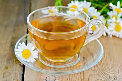 Herbal chamomile tea in a glass cup on a board
